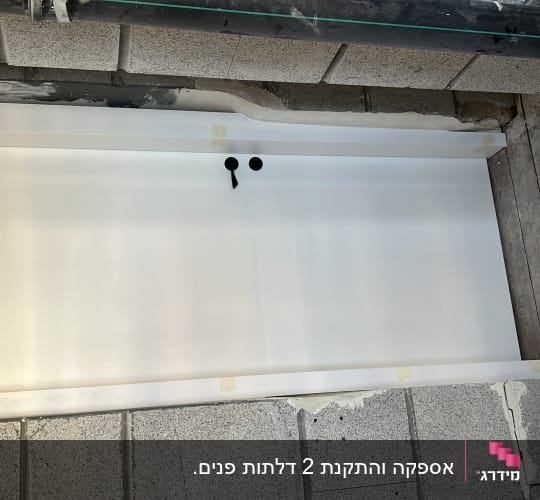 דלת לבנה עם חורים ליד קיר בטון